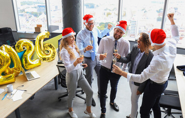 Business people are celebrating holiday in modern office drinking champagne and having fun in coworking. Merry Christmas and Happy New Year 2026