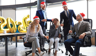 Business people are celebrating holiday in modern office drinking champagne and having fun in coworking. Merry Christmas and Happy New Year 2026
