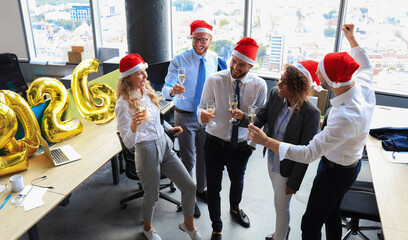 Business people are celebrating holiday in modern office drinking champagne and having fun in coworking. Merry Christmas and Happy New Year 2026