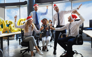 Business people are celebrating holiday in modern office drinking champagne and having fun in coworking. Merry Christmas and Happy New Year 2026
