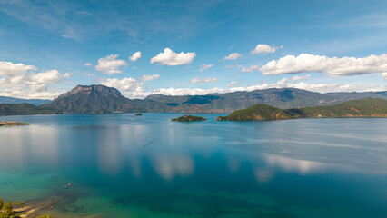 Obraz premium Villages by the Sunrise Lake and distant mountains, Lugu Lake in Sichuan, China