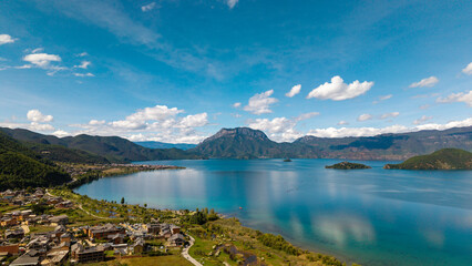 Naklejka premium Villages by the Sunrise Lake and distant mountains, Lugu Lake in Sichuan, China