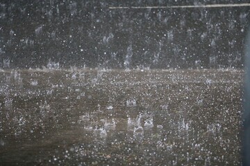 heavy rain falls on the street and splashes in the puddles
