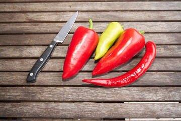 Messer, rote und grüne Spitzpaprika und eine Peperoni