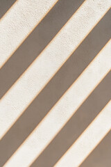Fototapeta premium Shadow stripes cascade across a textured surface, creating a visually striking pattern of light and dark. The contrast is both simple and captivating.