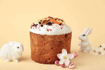Traditional easter cakes with colorful sprinkles, bunny figurine, and spring flowers on beige background.