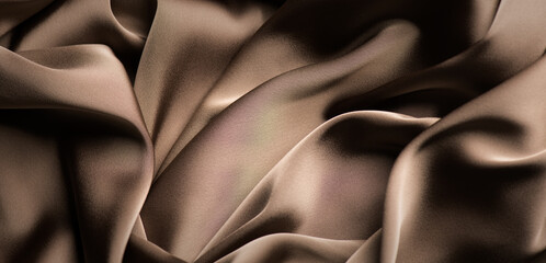 Silk, satin background. Chocolate brown color silk backdrop, folds, texture of beautiful dark beige satin fabric close-up. Abstract smooth elegant drapery folds. Top view