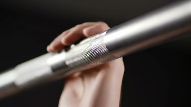 Close-up of textured silver metal barbell, fitness equipment for strength and workout on black background, promoting health and training.