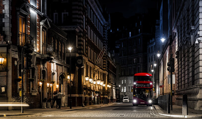 Classic red double-decker bus on festive London street at night