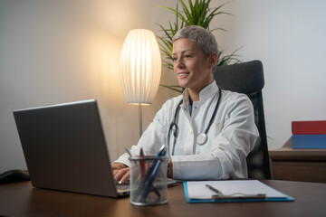 Female doctor with laptop working at the office desk.