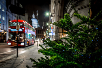 Naklejka premium Classic red double-decker bus on festive London street at night