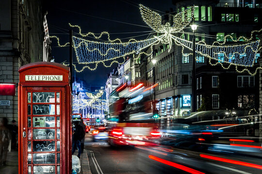 Classic red double-decker bus on festive London street at night