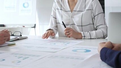 Business team analyzing financial charts and data reports during strategy meeting, hands pointing to documents on table with graphs and diagrams for planning - Powered by Adobe