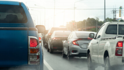 Rear side of pickup car blue color with turn on brake light. Environment of cars queue up in traffic jams. Pollution or fog after rain. Background of green tree and city. Queue up in traffic jams. 