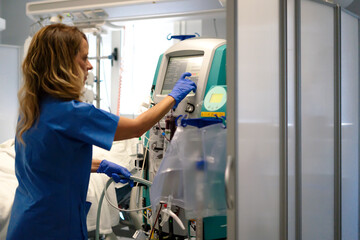 Nurse adjusting dialysis machine in hospital room