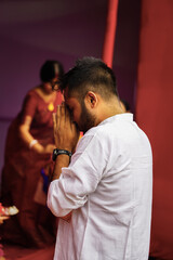 A boy wearing dark glasses and a Punjabi is greeting the puja
