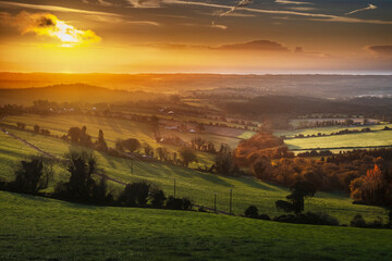 Scenic panoramic view of Irish farmland under dramatic orange and purple sky in early morning.