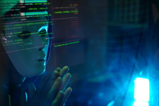 male hacker wearing a white mask sits in front of a screen, hands typing amid glowing cyber attack alerts and red binary code, symbolizing hacking, data breach, and malware concepts.