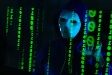 male hacker wearing a white mask sits in front of a screen, hands typing amid glowing cyber attack alerts and red binary code, symbolizing hacking, data breach hacker at work.