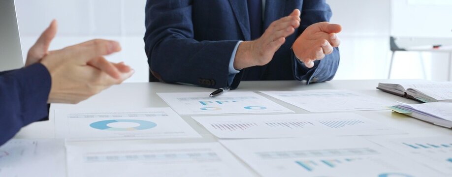Business team clapping hands in meeting celebrating success with financial charts, data analysis, sales growth reports, and teamwork achievement in modern office