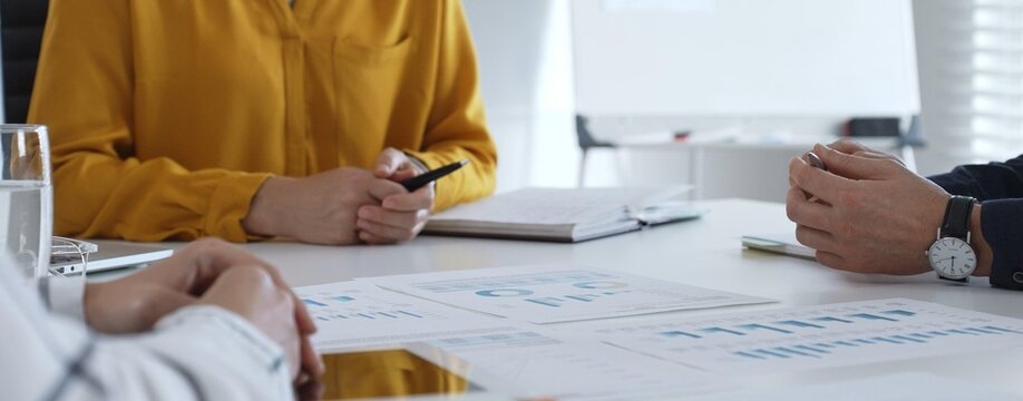 Business professionals gathered around conference table, reviewing financial charts, collaborating on strategic planning and corporate analysis