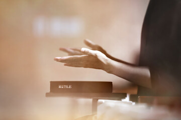 Worship and praise, believers raising their hands in prayer and meditation, the Holy Bible and church background
