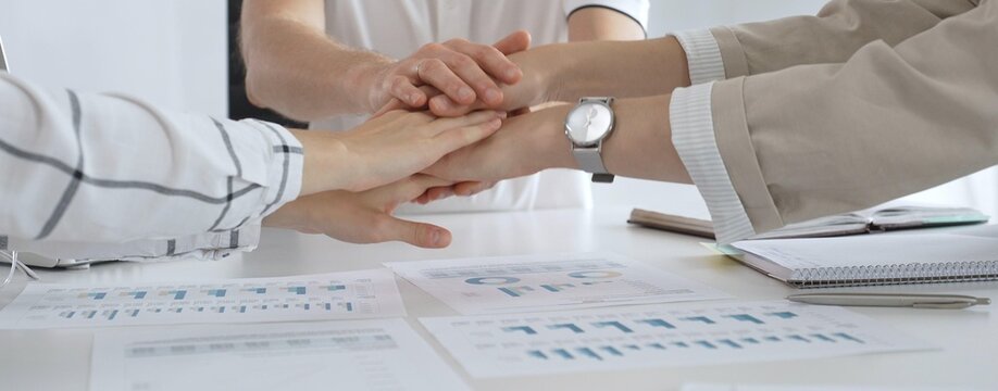 Businesspeople joining hands together, demonstrating unity, teamwork, and collaboration during a productive office meeting, fostering a strong and supportive work environment