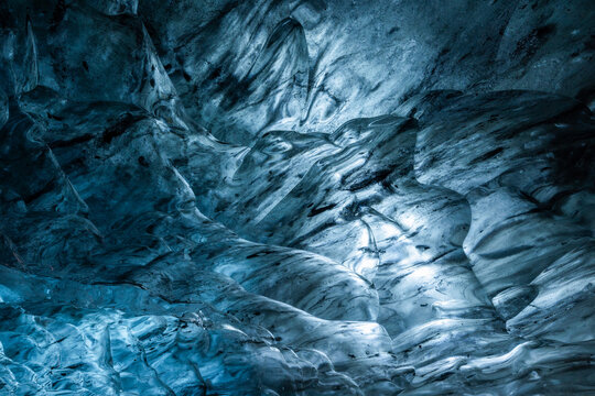 Stunning frozen blue glacier cave showing vibrant blue ice details and abstract patterns and bubbles
