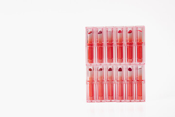 A row of pink lipsticks are displayed in a row. The lipsticks are all the same color and are arranged in a neat row. Concept of organization and order, as well as a focus on the beauty.