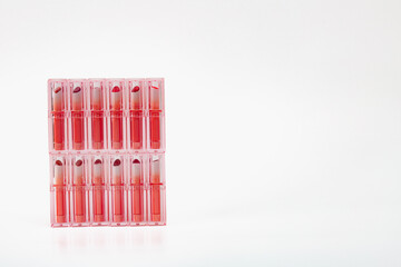 A row of pink lipsticks are displayed in a row. The lipsticks are all the same color and are in a clear container.