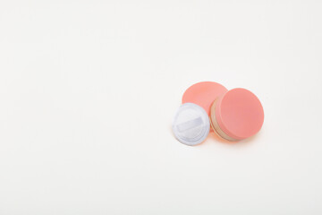 A white background with a pink and white makeup product. The makeup product is a powder puff. Concept of simplicity and elegance.