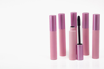 A row of six pink mascara tubes with a black wand in the middle. Concept of elegance and sophistication.