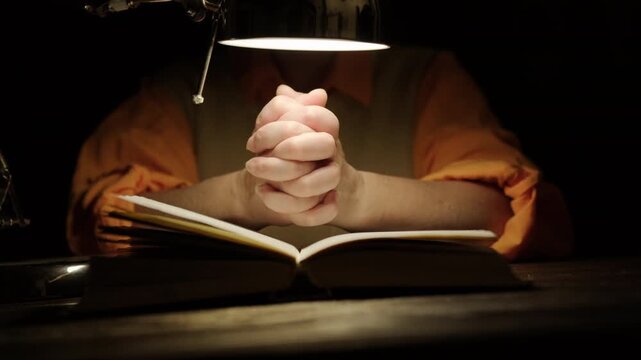Woman crosses hands in prayer over holy book, communicate with God, ask