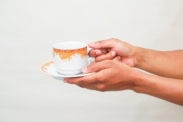 Aromatic Delight: Close-up of Hands Holding a Cup of Tea with Delicate Design