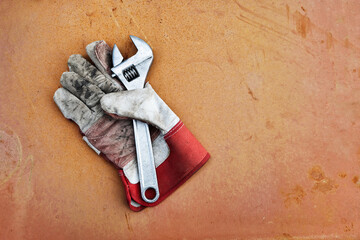 dirty glove with adjustable spanner on rusty surface
