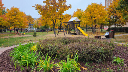Colorful autumn playground with slide and trees in neighborhood park  
