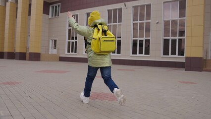 little girl run through the schoolyard to class, child rushing school building with school bag,...