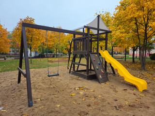 Playground structure with swings and slide in autumn park  
