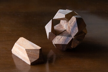 A wooden puzzle ball with one piece out of place on a wood table