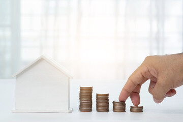 White house and man's fingers walking up the stairs, stacked coins and beautiful blurred background. Home loan concept, real estate business.