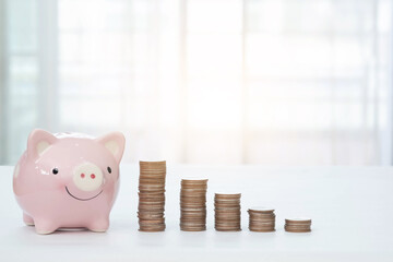 Pink piggy bank and stack of coins on window background. Money saving and finance business concept.