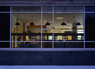 Empty cafe with large windows overlooking the pedestrian sidewalk on a winter evening
