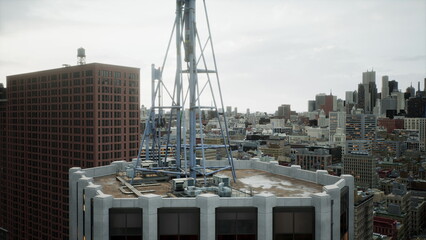 High above the bustling city, the rooftop reveals an antenna structure against a backdrop of skyscrapers beneath a cloudy sky. A mix of architecture tells the urban story.