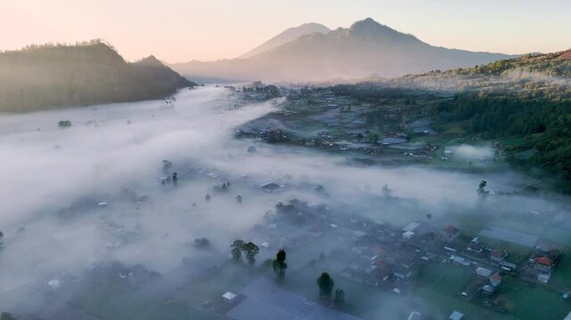 Drone video aerial view of Mount Batur, Bali, Indonesia with mist floating in the mountain valley in the morning