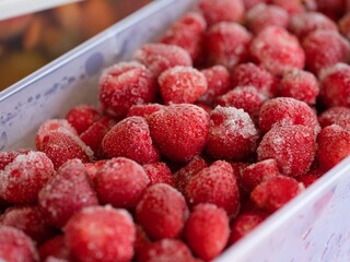 Frozen strawberries in a plastic container. Close-up