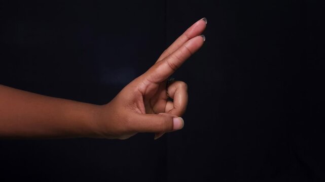 Close-up female hands expressing hand gesture with fingers isolated on black background.
