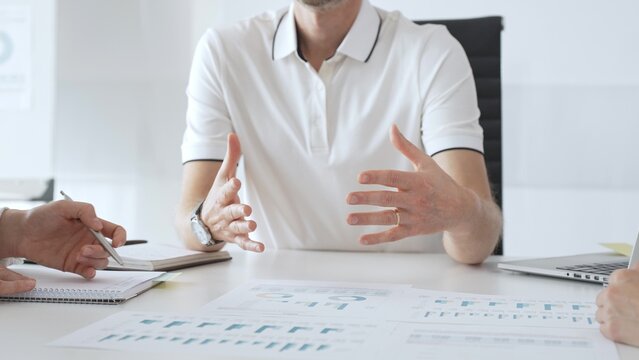 Business people team reviewing financial charts, collaborating intently around conference table in contemporary workspace, sharing insights during strategic planning session - Powered by Adobe