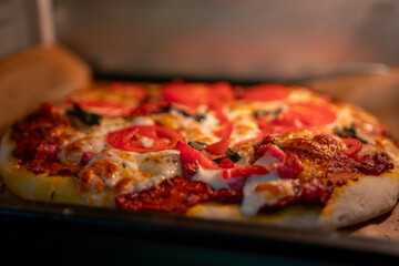 Pizza baking oven. Freshly baked pizza with tomatoes and melting cheese cooking in a hot home oven.