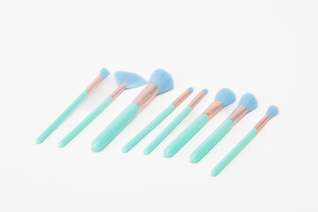 A set of green and blue makeup brushes. The brushes are lined up in a row, with the first brush being the leftmost and the last brush being the rightmost.