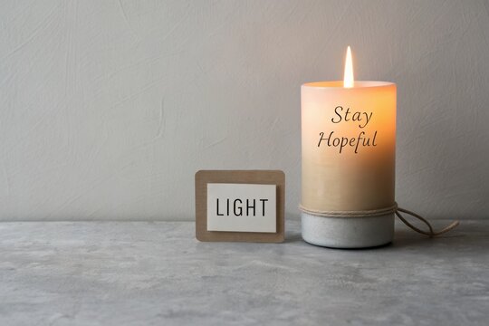 Glowing candle emitting light with hopeful message
